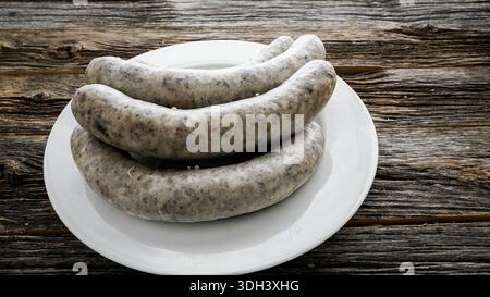 Fegato, pancetta di maiale e salsiccia di riso sono posti su un piatto bianco l'ambiente è un tavolo di legno, creando un'atmosfera rustica. Foto Stock