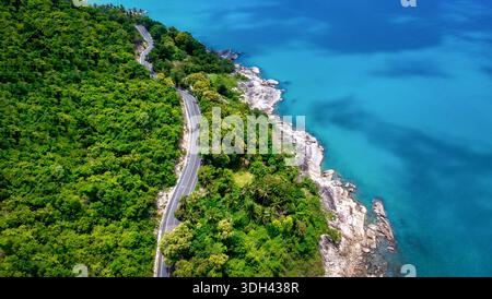 Vista aerea della strada tra palme da cocco e il grande oceano di giorno a Nakhon si Thammarat, Thailandia Foto Stock