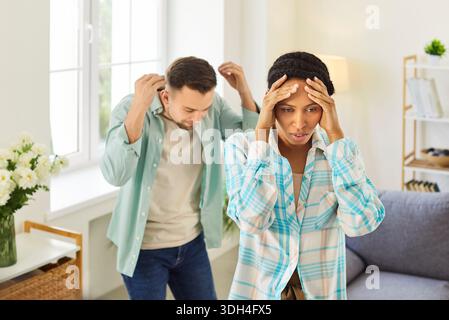 Stressata coppia di famiglia che litiga, la donna tiene la testa nella frustrazione Foto Stock