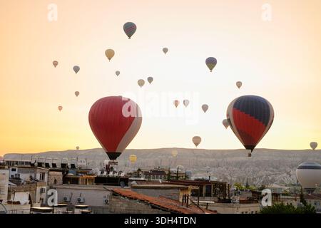 Giro in mongolfiera sui siti storici, sorvolando le formazioni rocciose illuminate dall'alba e i tetti della Cappadocia. Giro in mongolfiera, tour, turismo Foto Stock
