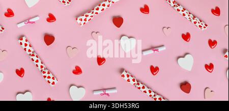 Simpatico banner di San Valentino con cuori rosa, bianco e rosso e piccole borse regalo su sfondo rosa pastello Foto Stock