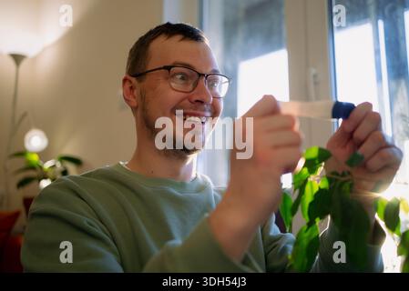 Uomo che tiene un test di gravidanza, reagisce con un sorriso felicissimo e stupito mentre riceve notizie di imminente genitorialità, esprimendo felicità e sorpresa per la nuova aggiunta di famiglia Foto Stock
