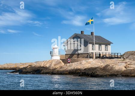 Vista dall'acqua della luce del porto e dell'edificio costiero in legno sulla costa rocciosa all'ingresso settentrionale del porto di Marstrand, Bohuslän, costa occidentale della Svezia Foto Stock