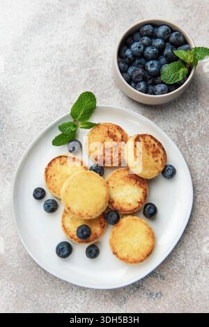 Frittelle di sciroppo dorato con mirtilli freschi e menta per una deliziosa colazione Foto Stock