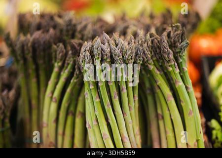 Un primo piano di lancette di asparagi verdi fresche disposte ordinatamente in un mercato biologico. Il vivace colore verde ne mette in risalto la freschezza e la nutrizione Foto Stock