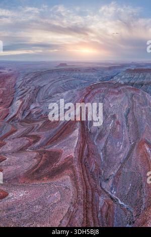 Accattivante vista aerea dei tortuosi canyon del fiume San Juan durante il tramonto nello Utah, Stati Uniti. Le formazioni rocciose a strati mostrano vibranti tonalità della terra Foto Stock