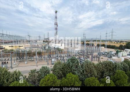 La vista aerea cattura una grande centrale elettrica con diverse torri ad alta tensione e un'estesa infrastruttura elettrica. Il complesso e' posto contro a. Foto Stock