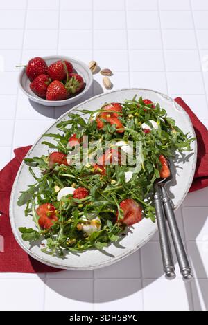 Un'insalata vibrante con rucola fresca e fragole succose abbinate a mozzarella cremosa e pistacchi croccanti. Rifinito con un balsamico piccante vi Foto Stock
