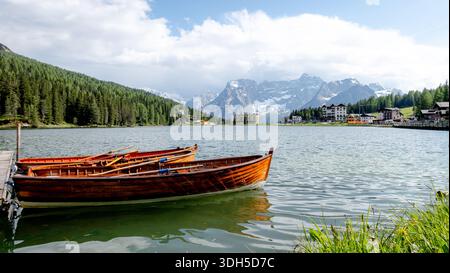 Le barche riposano sulle tranquille acque del Lago di Misurina, circondato dalle maestose cime delle Dolomiti. Ambiente tranquillo con foreste lussureggianti e alpe Foto Stock