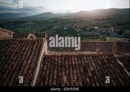Vista aerea di un'incantevole cittadina italiana con tetti rustici e lussureggiante campagna verde. Questa fotografia con drone cattura la bellezza serena Foto Stock