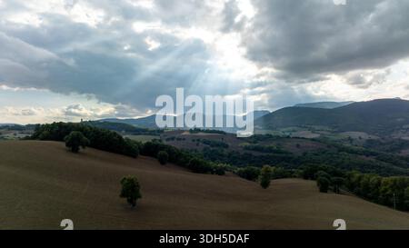 Vista aerea di una tranquilla campagna italiana con colline ondulate e vegetazione lussureggiante sotto un cielo spettacolare. Scattata con la fotografia con drone, evidenziazione Foto Stock