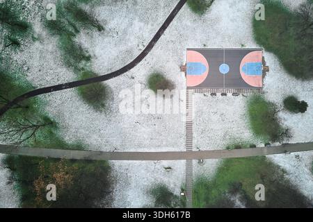 Vista sul campo da pallacanestro all'aperto e sul parco coperto di neve Foto Stock