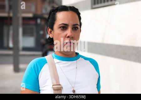 Donna adulta che cammina lungo una strada della città con un'espressione seria Foto Stock