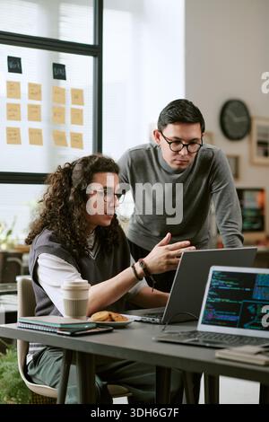 Giovani colleghi caucasici che collaborano al progetto di sviluppo software Foto Stock