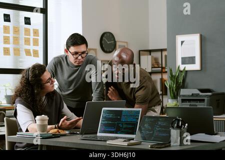 Giovani team multietnici che discutono le strategie di sviluppo software in ufficio Foto Stock