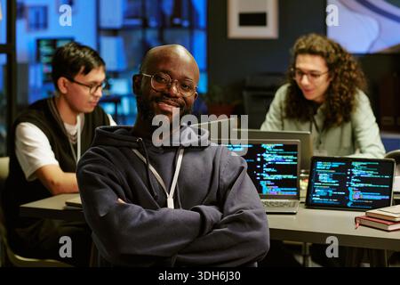 Ritratto del giovane Black Man sorridente mentre lavora con diversi Team Foto Stock