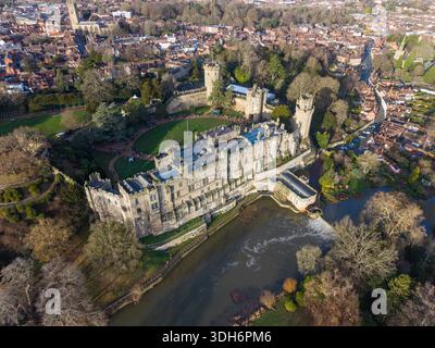 Vista aerea delle mura e delle torri di pietra del castello di Warwick che si riflettono nel tranquillo fiume Avon, circondato dalle vivaci sfumature del fogliame autunnale, Warwic Foto Stock