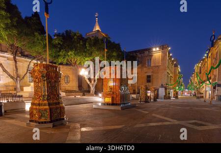 Republic Street a la Valletta Malta illuminata e decorata per feste con tradizionali piedistalli e ghirlande verdi Foto Stock