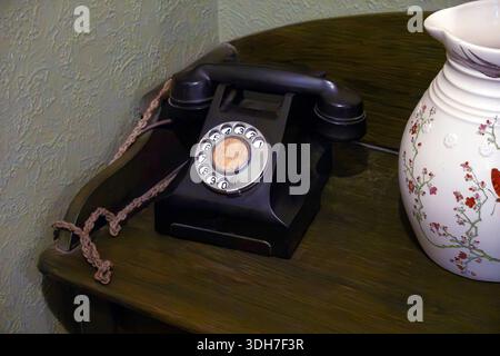 Telefono con quadrante rotativo vintage su scrivania in legno con vaso Foto Stock
