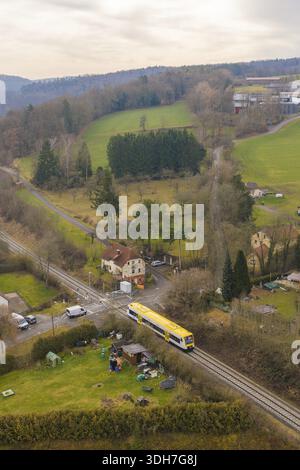 Scena rurale con treno giallo nella campagna verde e case sparse, accettazione della ferrovia Hermann Hesse, Calw, Foresta Nera, Germania Foto Stock
