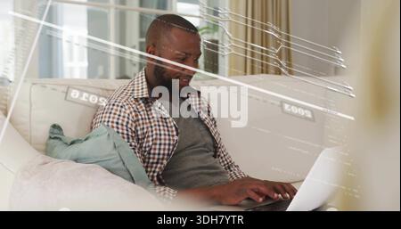 Uomo maturo che indossa una camicia a scacchi su un computer portatile sul divano nel soggiorno, con cuscino Foto Stock