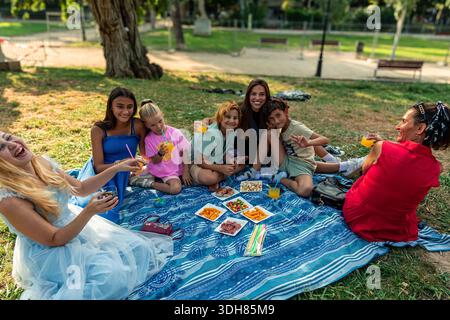 Famiglia felice che si diverte a fare un picnic in un parco cittadino Foto Stock