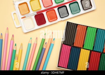 Matite colorate, plasticine e vernici ad acquerello su sfondo beige. Vista dall'alto Foto Stock
