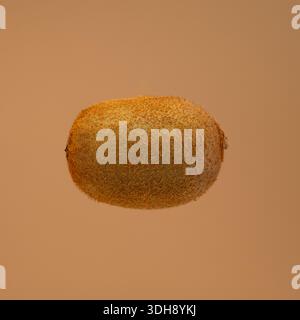 Un kiwi è mostrato nell'aria. Il frutto è marrone e sfocato. Il kiwi è sospeso nell'aria, dando l'impressione che galleggi Foto Stock