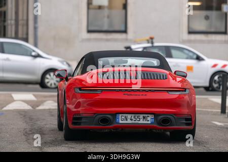 Nancy, Francia - Vista su una Porsche 992 Carrera 4S Cabriolet rossa che guida su una strada con auto parcheggiate sullo sfondo. Foto Stock