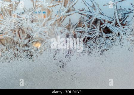 Motivi gelidi sul cristallo del finestrino. Gli schemi sembrano piume di cigno. Texture naturale astratta in inverno. Foto Stock