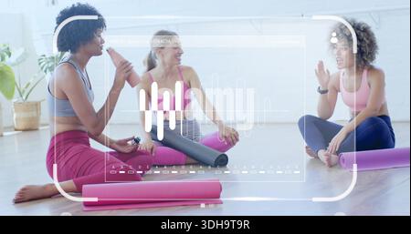 Trio seduto in abbigliamento atletico che chiacchiera in uno studio luminoso con tappetini, roller e HUD Foto Stock