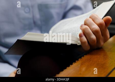 Primo piano di mani che leggono la Sacra Bibbia che legge la Bibbia in casa Foto Stock
