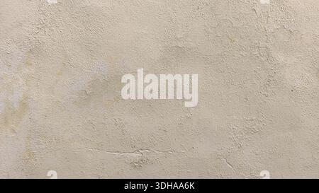 Primo piano di una parete in gesso beige resistente agli agenti atmosferici con una trama ruvida e granulosa, sottili crepe e macchie irregolari, ideale per l'uso su sfondo. Foto Stock