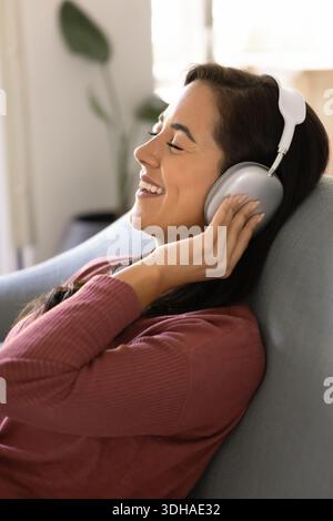 Donna felice che ascolta la musica con le cuffie moderne Foto Stock