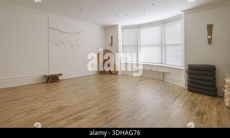 Studio yoga vuoto, spazioso e luminoso, con pavimenti in legno duro, grandi finestre bovindo e oggetti di meditazione ben organizzati. Foto Stock