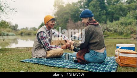 Sorridi, coppia e picnic con caffè all'aperto per viaggi, bevande calde e avventura di trekking. Felice, gente e campeggio con drink per colazione Foto Stock