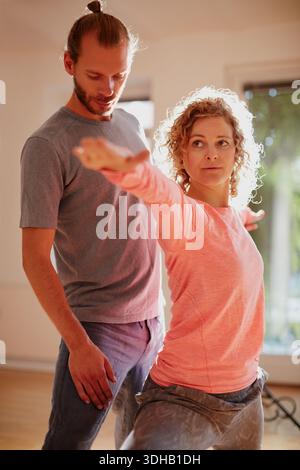 Yoga, insegnamento e stretching con persone in studio per fitness, posa guerriera e pratica di guarigione. Equilibrio olistico, virabhadrasana e apprendimento con Foto Stock