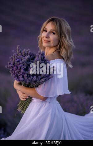 Donna Lavanda campo Provenza Estate: Elegante donna tiene il bouquet di lavanda, posa in un campo di lavanda viola durante l'estate in Provenza. Foto Stock
