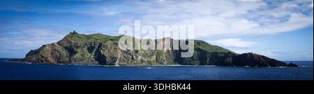 La vista di un'isola aspra con scogliere ripide e vegetazione lussureggiante sorge drammaticamente dal mare blu profondo, Adamstown, British Overseas Territory i Foto Stock