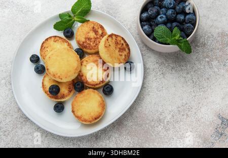 Frittelle di sciroppo dorato con mirtilli freschi e menta per una deliziosa colazione Foto Stock