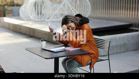 risate gioiose nel parco urbano mentre una giovane donna ama momenti di cuore con le lettere Foto Stock