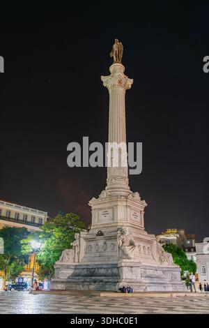 Lisbona, Portogallo - 12 ottobre 2025: Vista notturna dall'angolo basso della colonna monumentale di Pietro IV nel centro di Piazza Rossio. Foto Stock