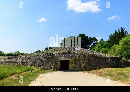 Locmariaquer, Francia - 1 giugno 2023: L'ingresso al Dolmen de la Table des Marchands, una tomba megalitica preistorica con un tumulo di pietra e porta, è visibile sotto un cielo azzurro. Foto Stock