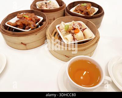 Set dim sum con piatti cotti a vapore e tè su White Table Foto Stock