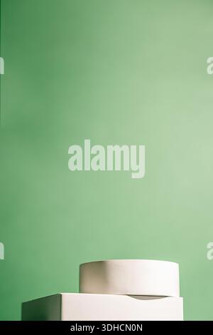 I podi cilindrici e rettangolari di colore bianco minimo sono posizionati su uno sfondo verde tenue. Perfetto per mostrare prodotti per la cura della pelle, cosmetici, prodotti ecologici o modelli di branding moderni Foto Stock
