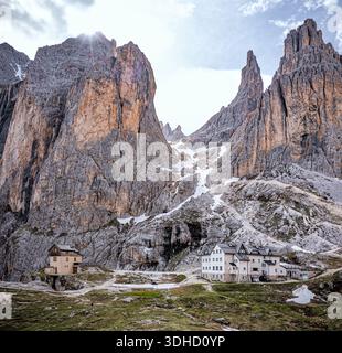 Veduta aerea delle spettacolari torri Vajolet frastagliate vette che torreggiano su pittoreschi edifici annidati nella valle, le loro pareti rocciose contrastano con le macchie Foto Stock