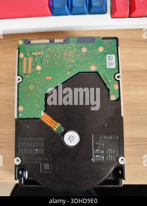 Componente interno del disco rigido su una superficie in legno con tastiera sullo sfondo Foto Stock