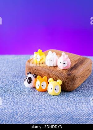 Un primo piano di una serie di adorabili statuette colorate in stile kawaii, poste su un palco di legno Foto Stock
