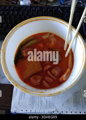 Ciotola di zuppa piccante di spaghetti asiatici con bacchette sulla scrivania Foto Stock