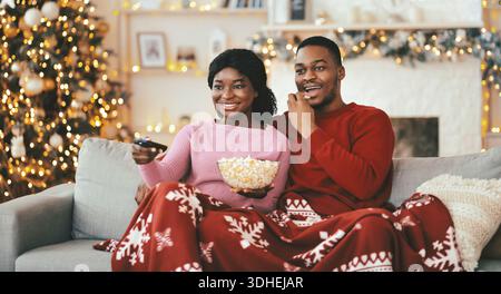 La coppia si diverte a una serata al cinema con popcorn sul divano durante la stagione invernale Foto Stock